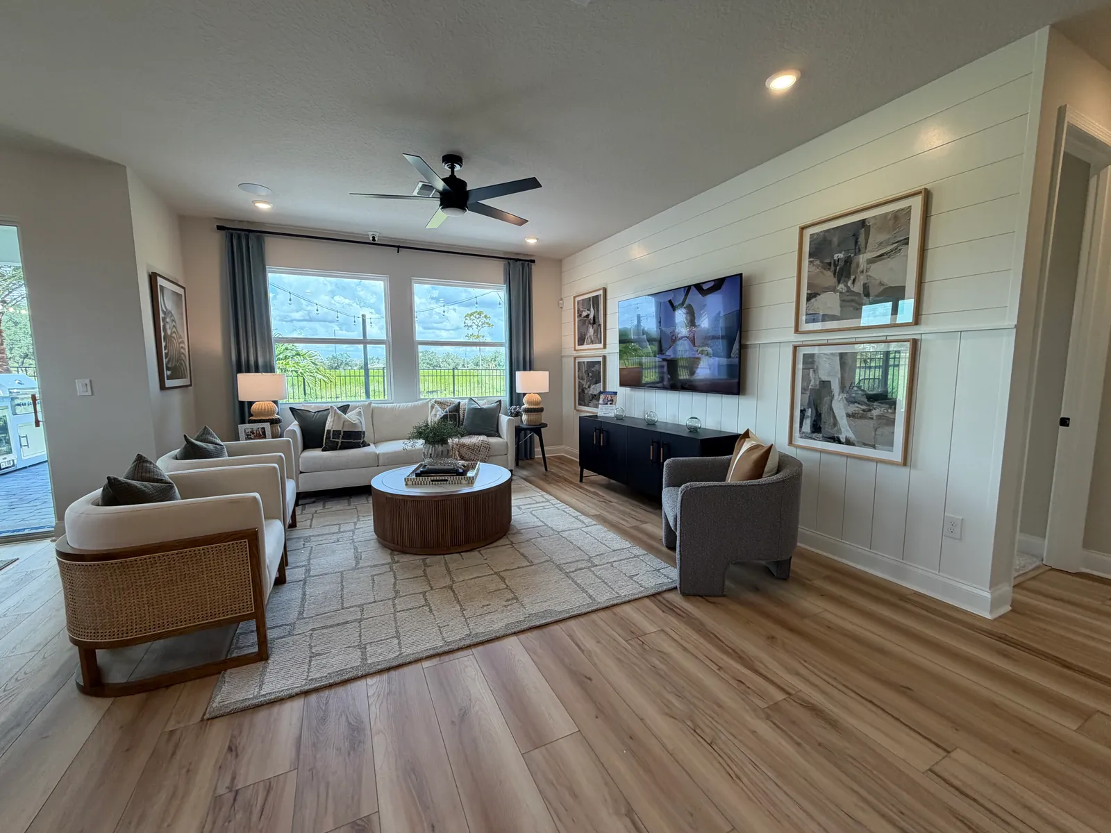 Sala amplia de una casa modelo con piso de madera y ventanales